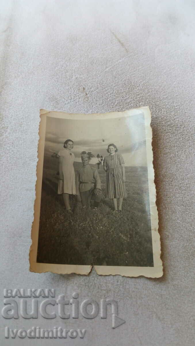 Photo A soldier and two young women on the grass