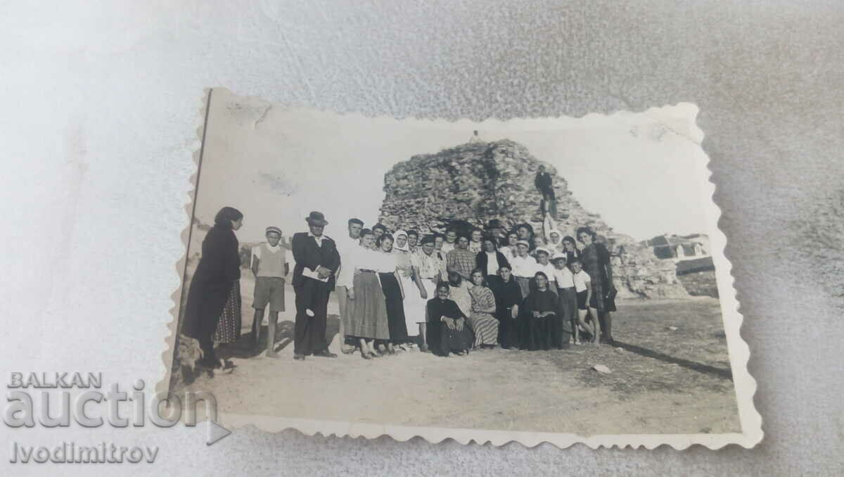 Foto Bărbați, femei și copii în fața unui morman de pietre