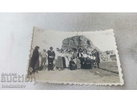 Photo Men, women and children in front of a pile of stones