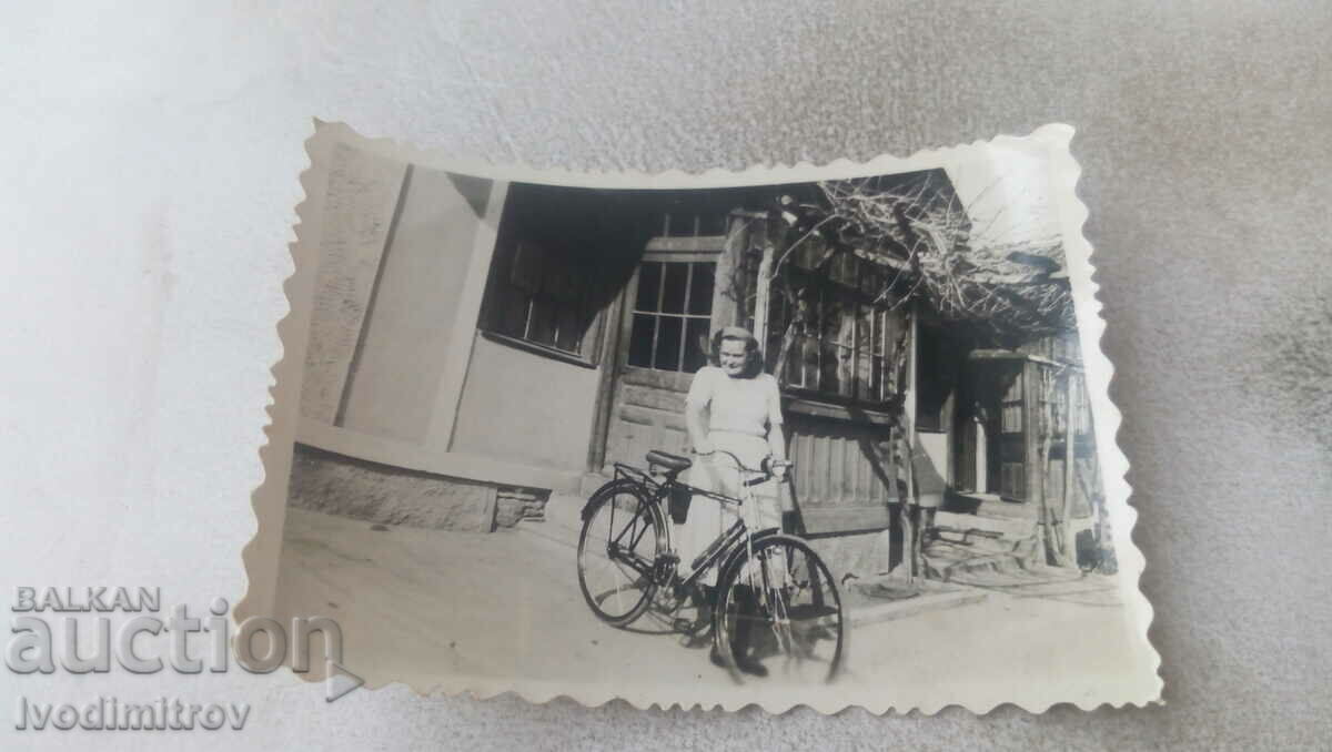 Fotografie Tânără cu o bicicletă de epocă pe trotuar