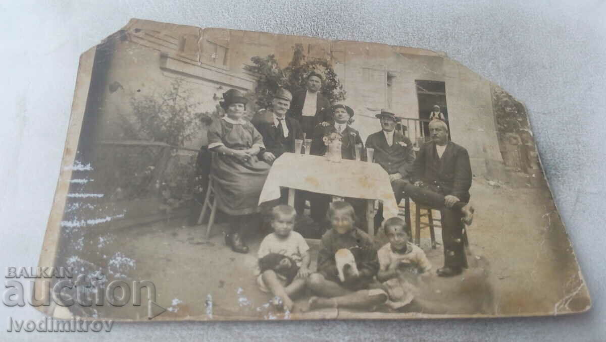 Picture Men, woman and children with three cats around a table