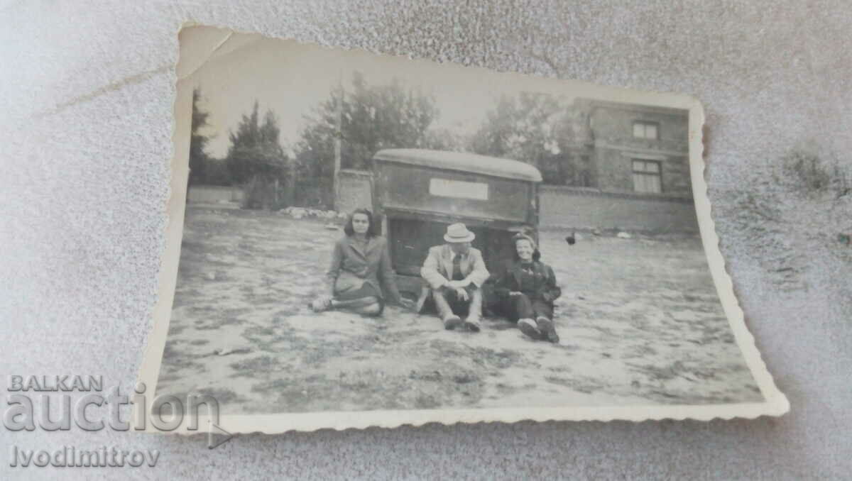 Photo A man and two women sitting in front of a truck cab