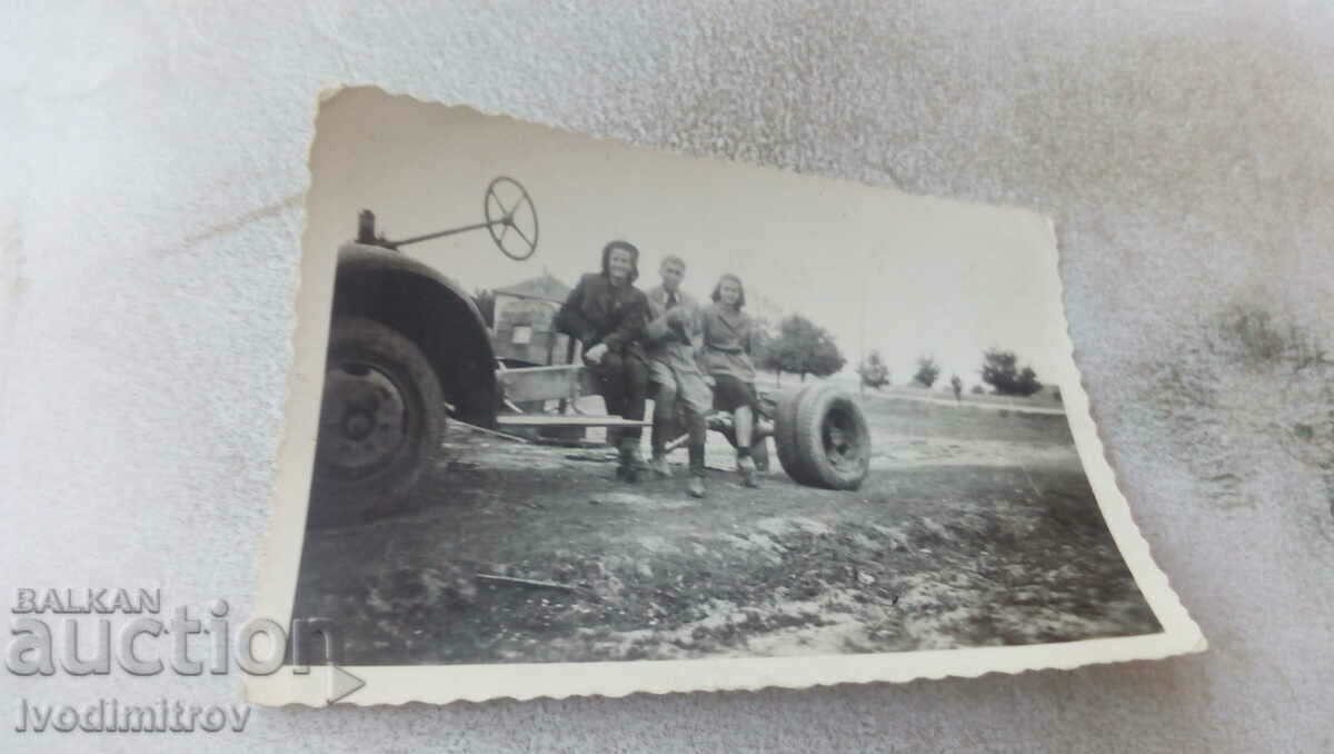 Fotografie Un bărbat și două femei pe șasiul unui camion