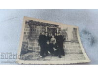 Mrs. Lovech Pupils and a boy on the sidewalk next to the fence of a yard