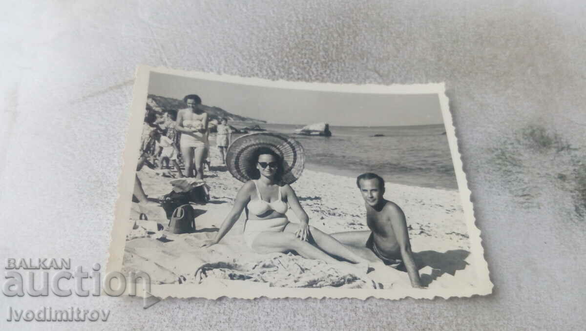 Photo A man and a woman with a wide-brimmed hat on the beach