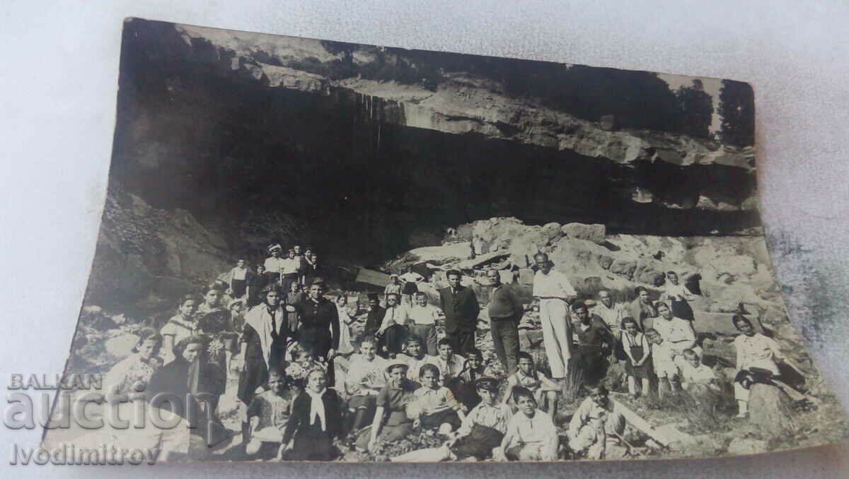 Photo Men, women and children in front of a cave