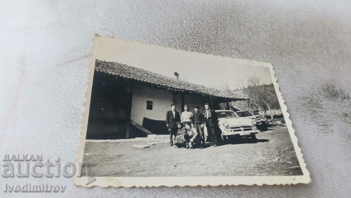 Doamna bărbați, tinere și o mașină în curtea unei case de țară