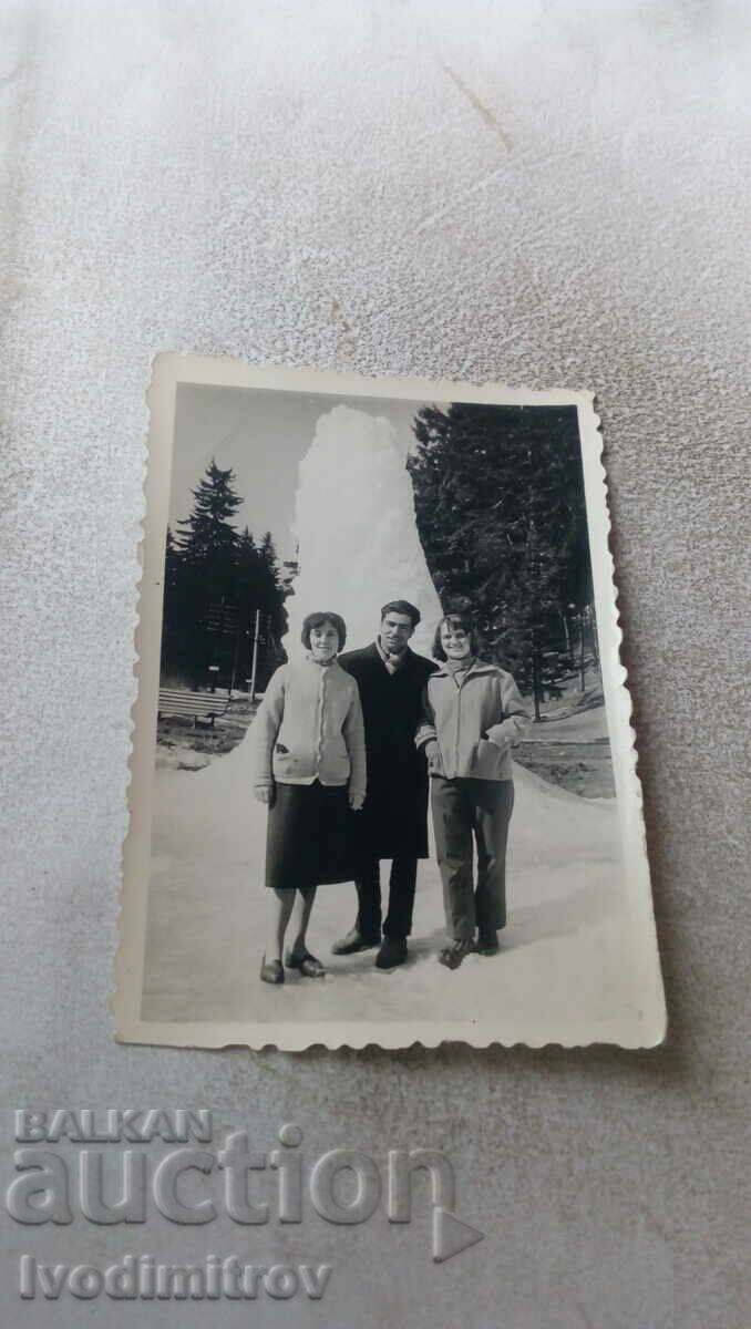 Photo A man and two women in front of a huge pile of snow in the park