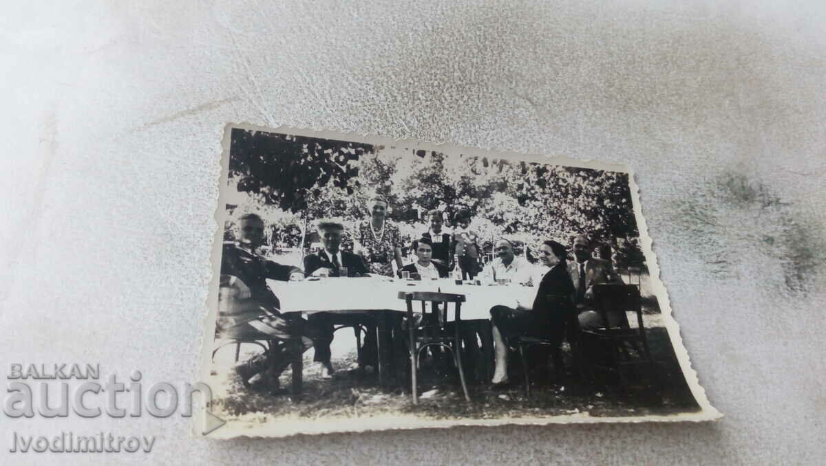 Foto Bărbați și femei în jurul unei mese în grădină