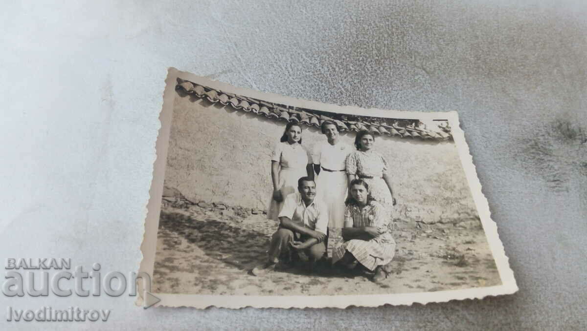 Φωτογραφία Ένας άντρας και τέσσερα νεαρά κορίτσια δίπλα σε έναν τοίχο