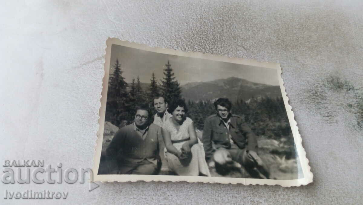 Foto Trei bărbați și o femeie pe o stâncă în munți