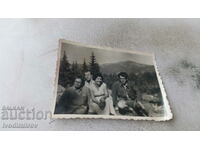 Photo Three men and a woman on a rock in the mountains