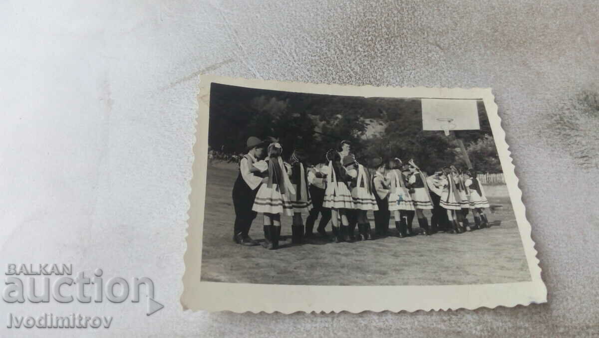 Ms. Boys and girls in folk costumes next to a basketball hoop