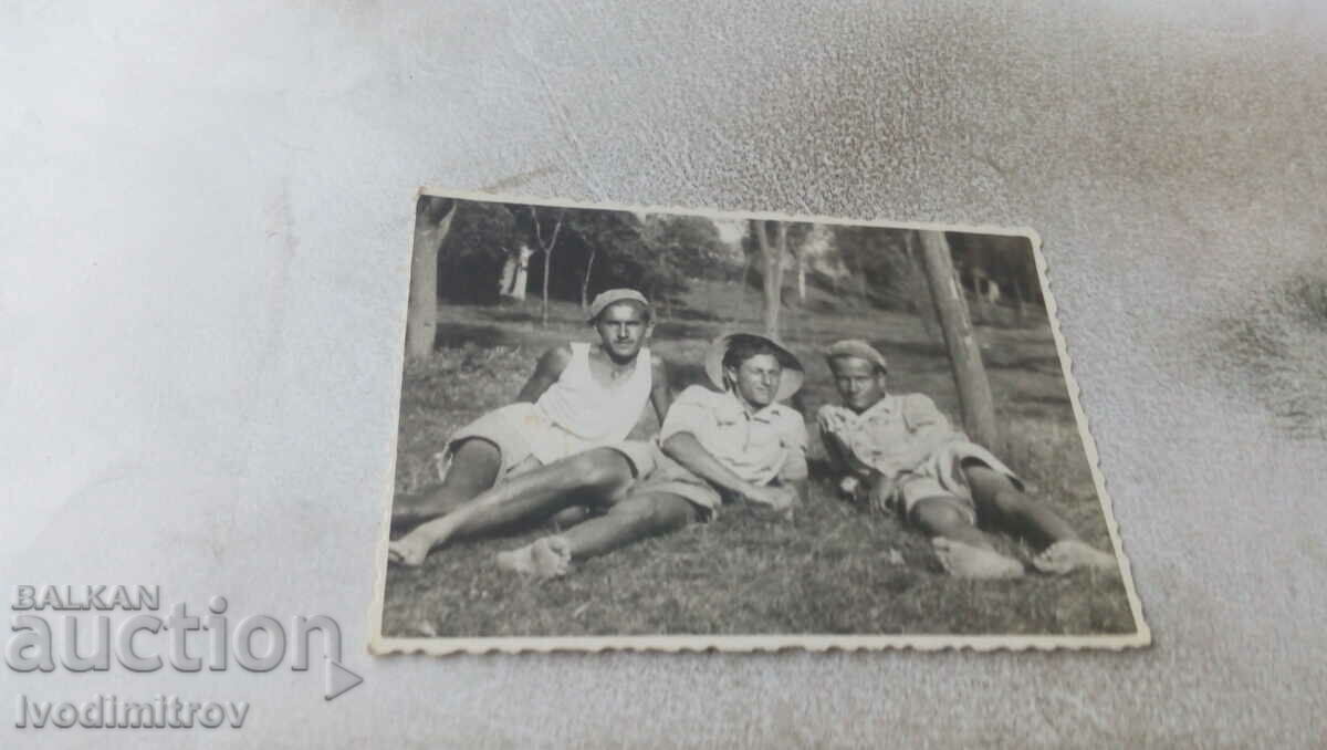 Foto Trei bărbați întinși pe gazon