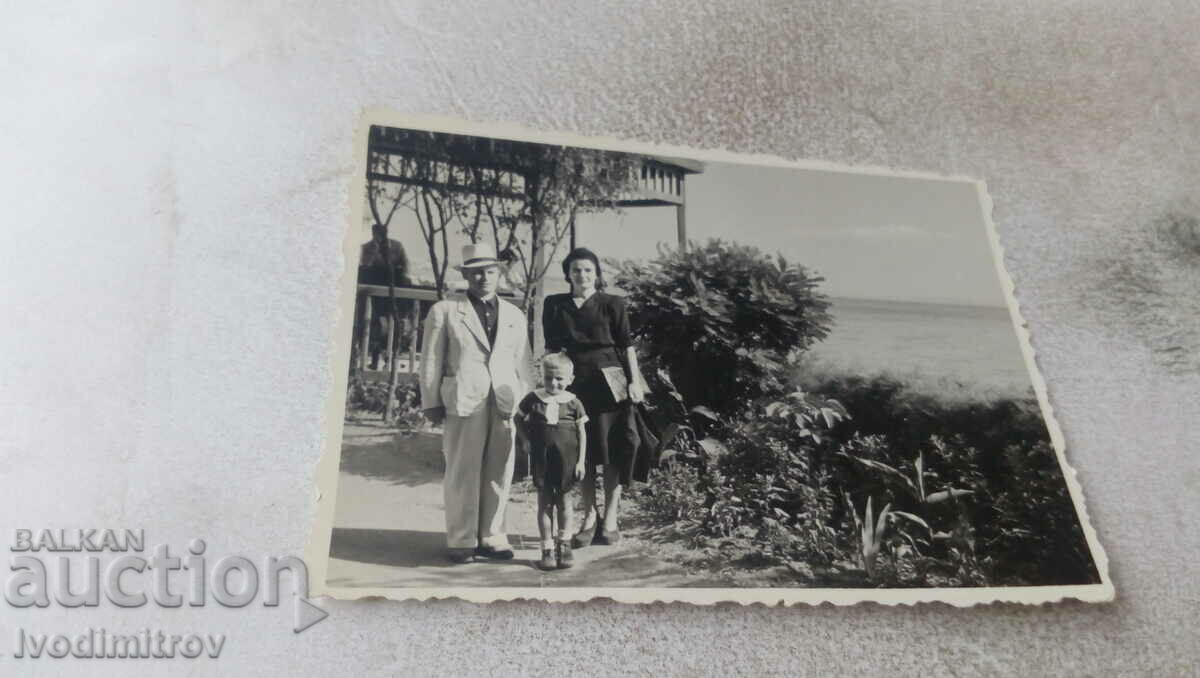 Φωτογραφία Ένας άντρας, μια γυναίκα και ένα αγοράκι μπροστά σε ένα κιόσκι δίπλα στη θάλασσα