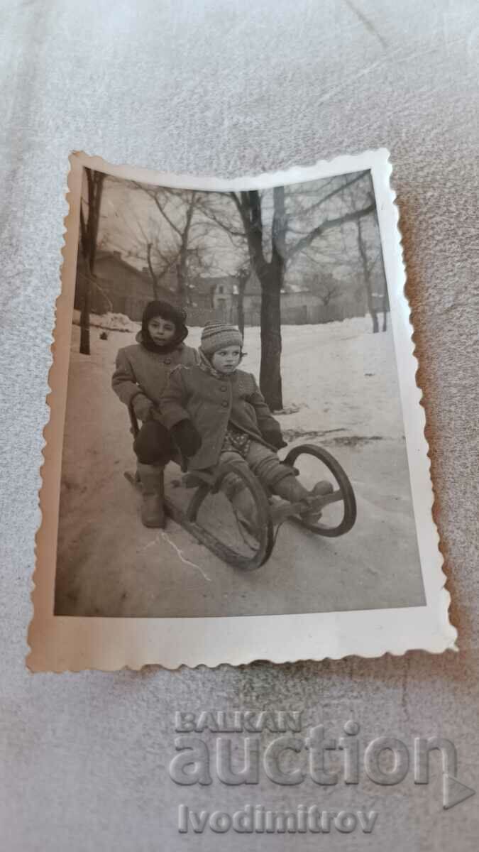 Κα Ρούσε Ένα αγόρι και ένα κορίτσι με ένα ξύλινο έλκηθρο στο πάρκο το χειμώνα