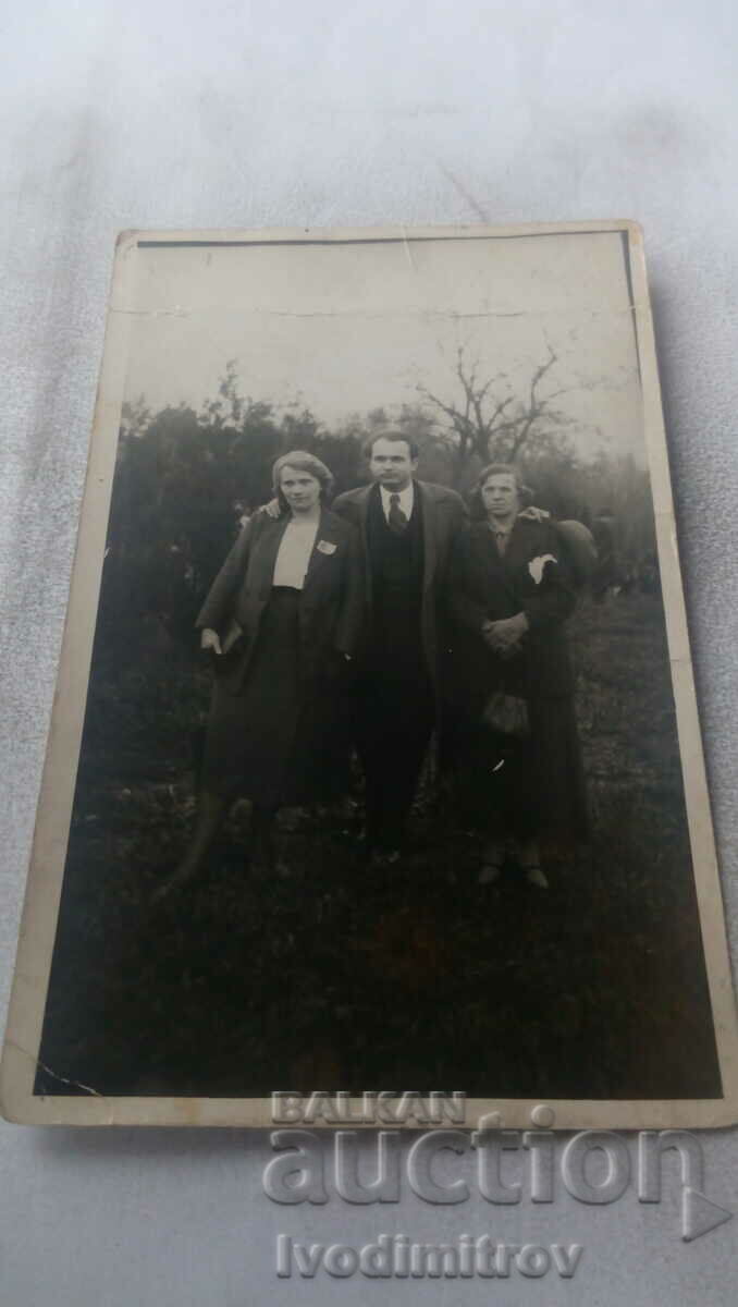 Photo A man and two women in an orchard