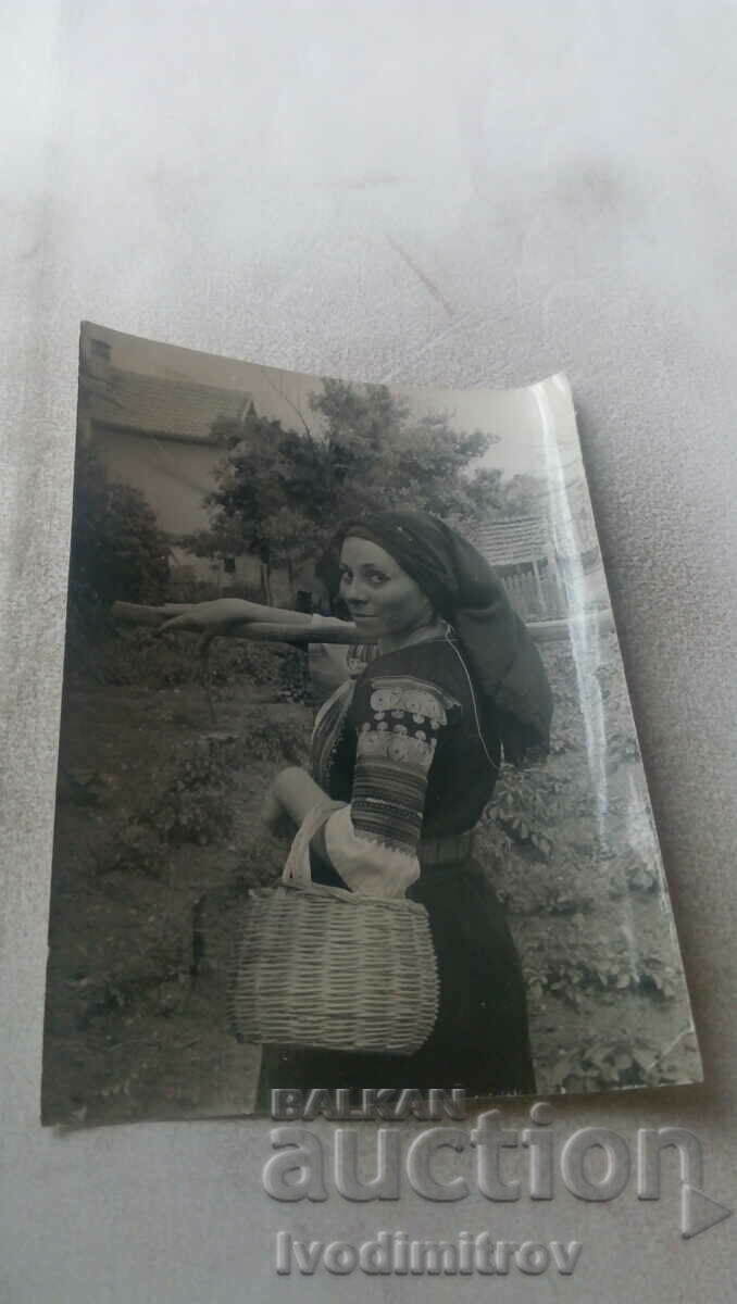 Photo Woman with a wicker basket and a hoe on her shoulder