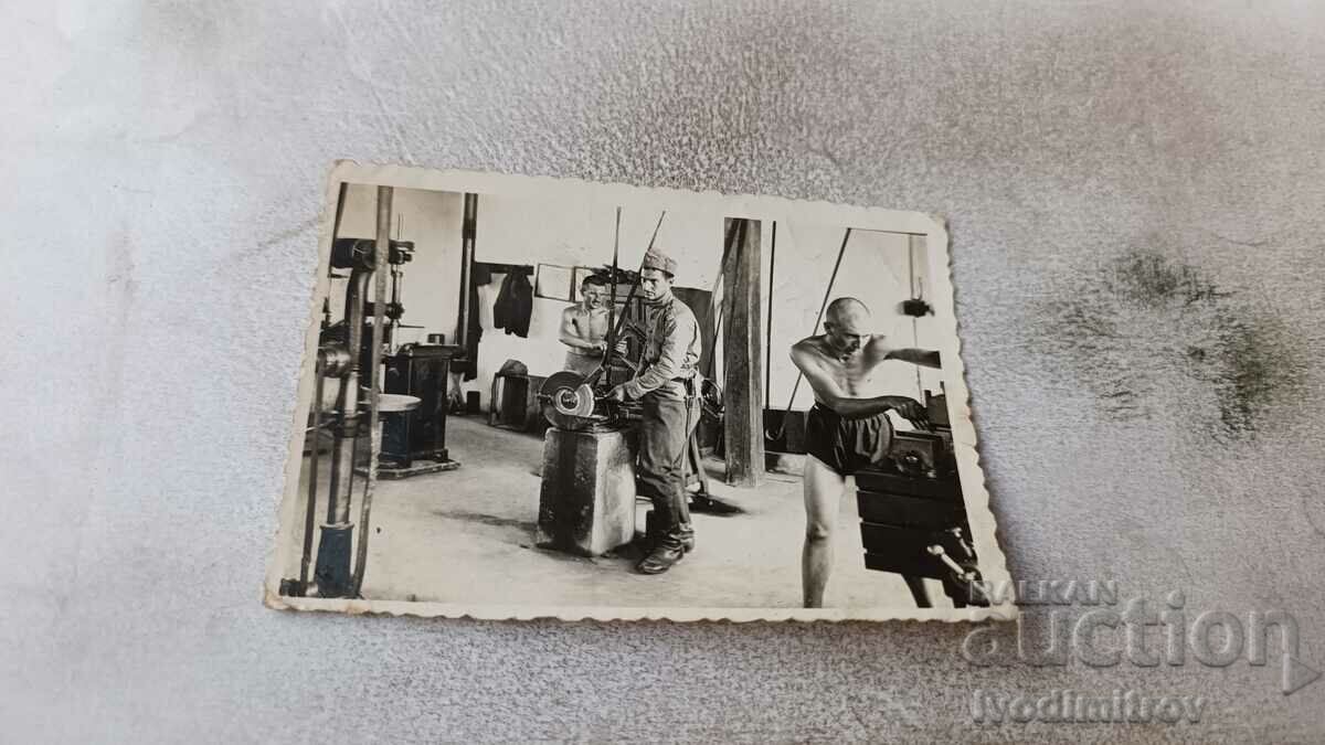 Foto Trei soldați într-un atelier de strung