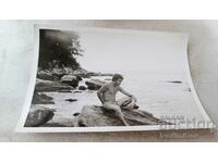 Photo A man in a swimsuit on a rock on the seashore