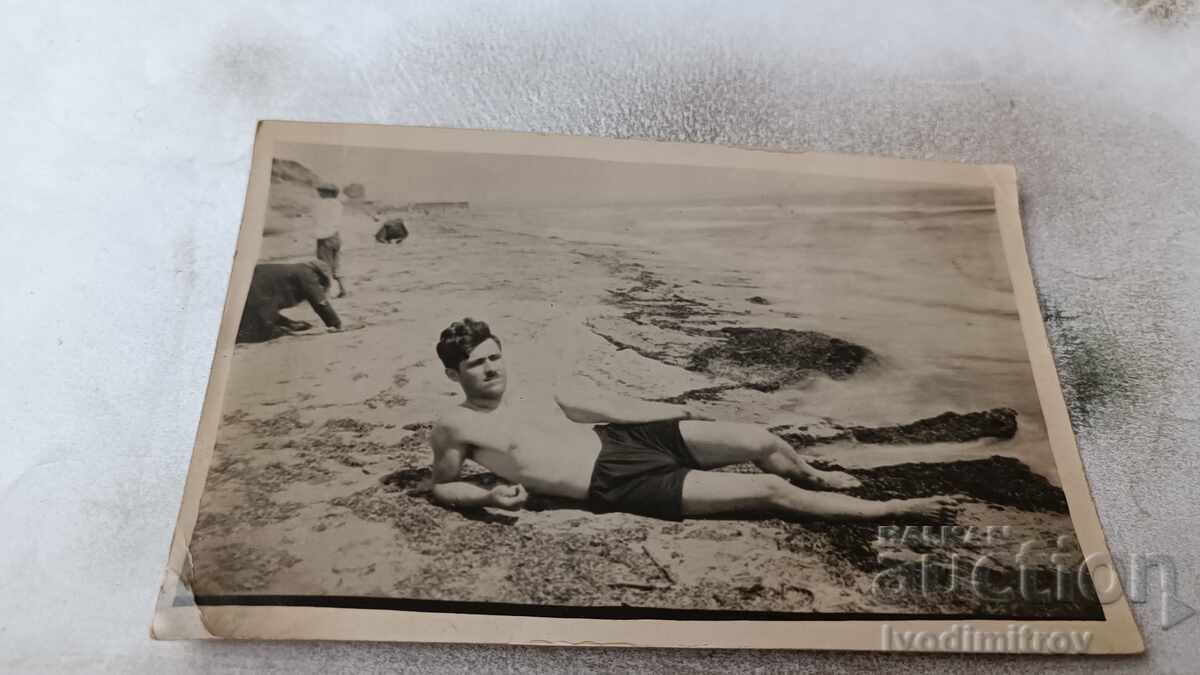 Photo A man in a retro swimsuit lying on the beach
