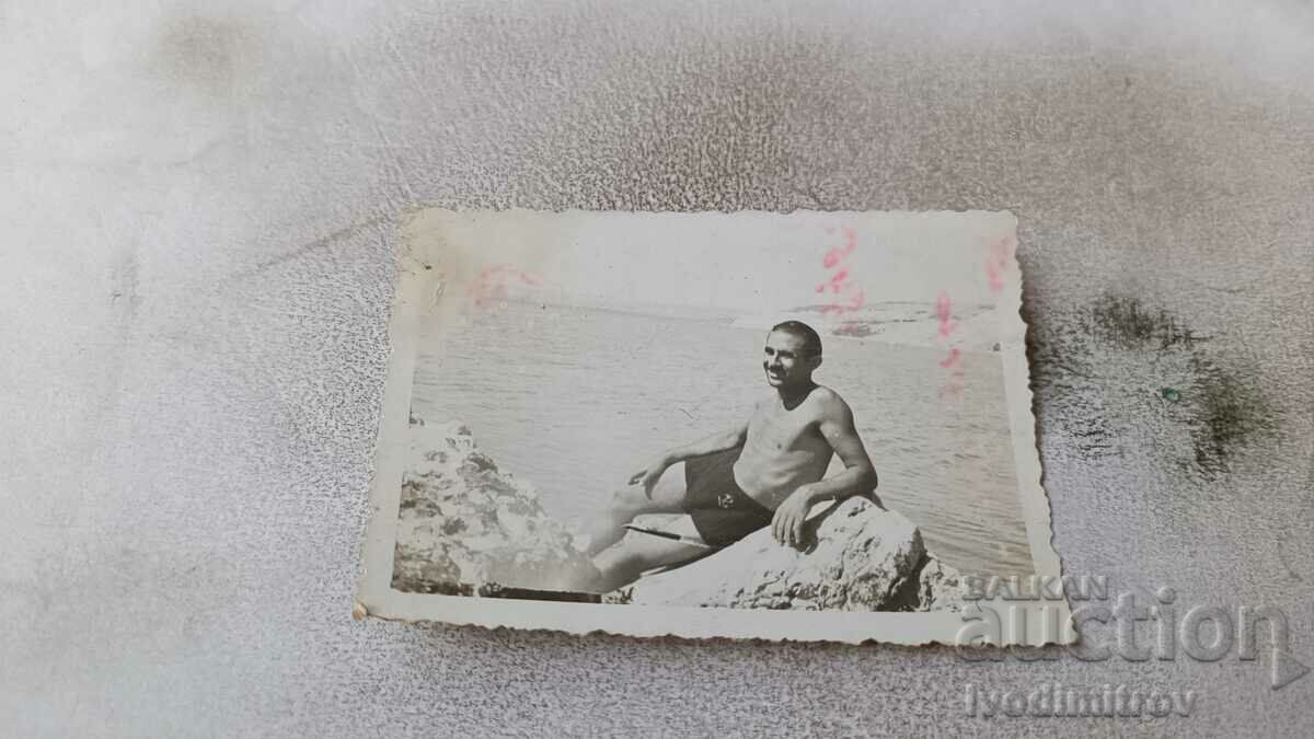 Снимка Мъж с ретро бански на скала до морето