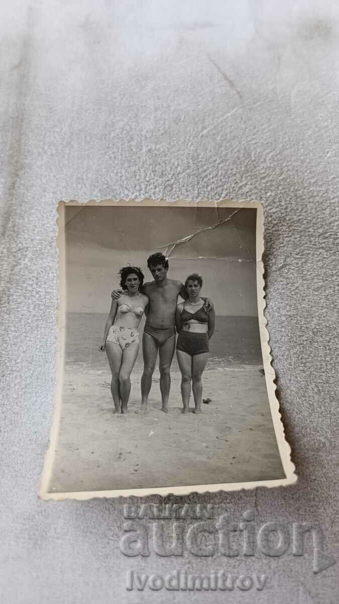 Photo A young man and two young girls on the beach