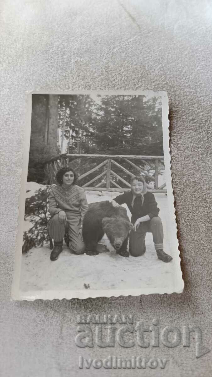 Снимка Две млади момичета до препарирана кафява мечка