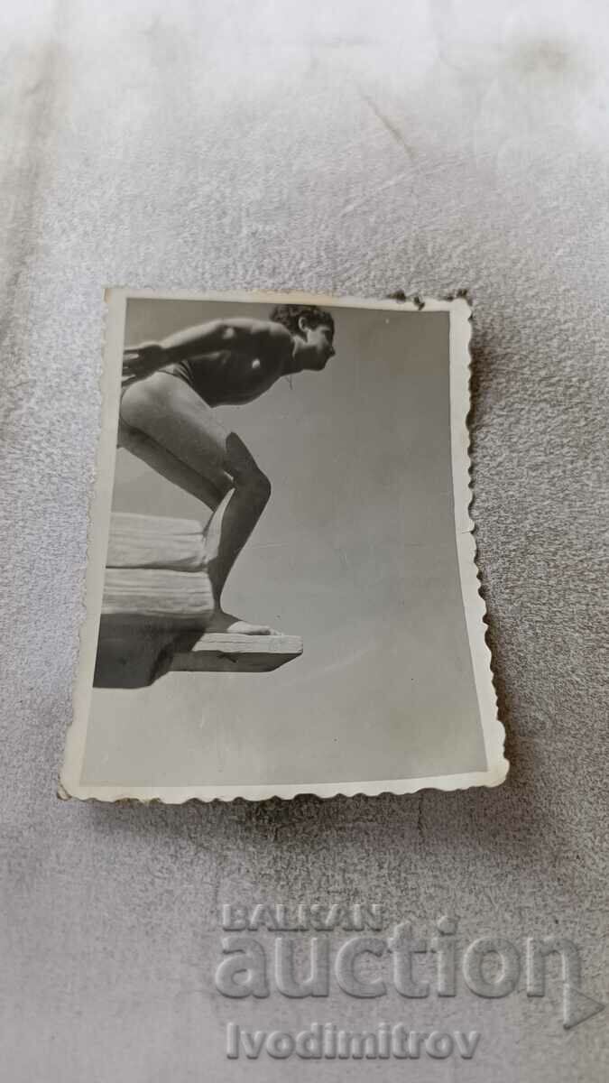 Снимка Млад мъж скачащ от трамплин на плувен басейн