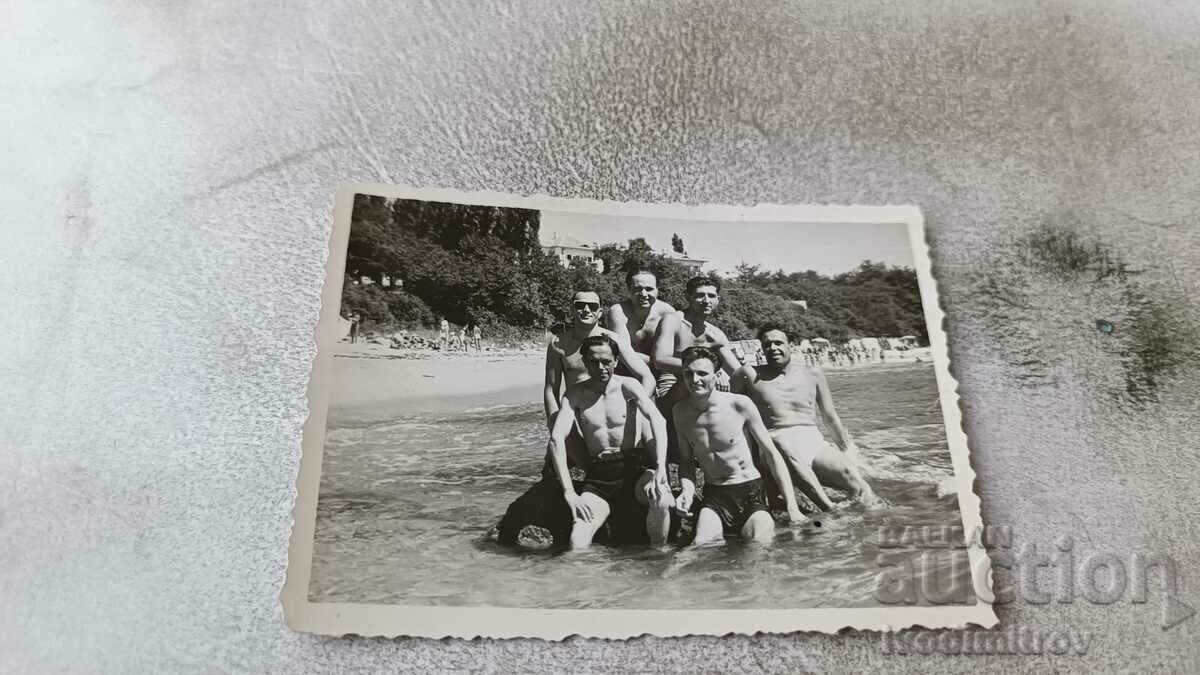 Photo Seven men on a rock on the seashore