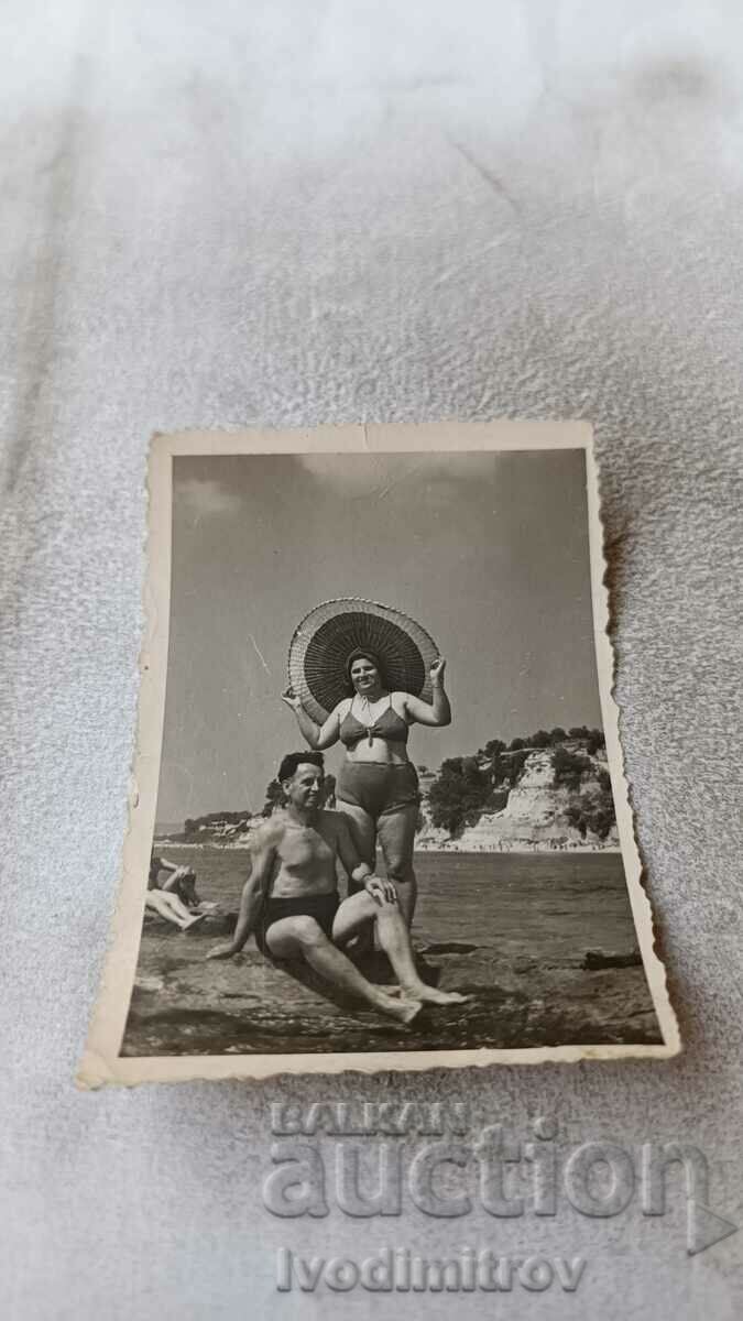 Photo Man and woman with sombreros on a rock by the seashore