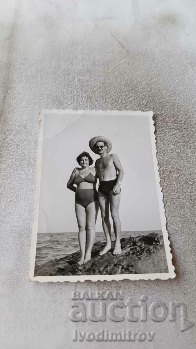 Φωτογραφία Άνδρας και γυναίκα με μαγιό σε έναν βράχο δίπλα στη θάλασσα