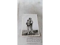 Photo Man and woman in swimsuits on a rock by the sea