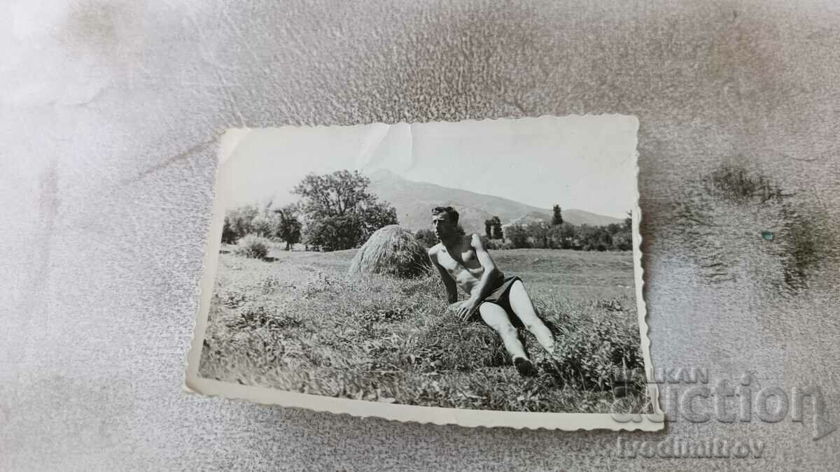 Снимка Мъж с къси панталони полегнал на тревата