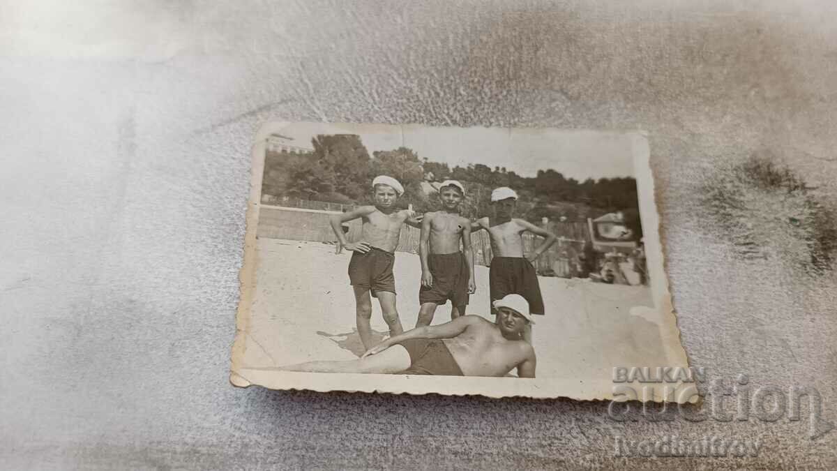 Photo A man and three boys in vintage swimwear on the beach