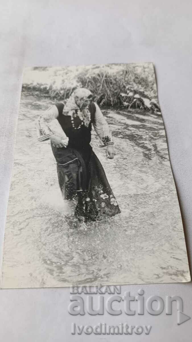 Fotografie Femeie în costum popular într-un râu furibund