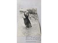 Fotografie Femeie în costum popular într-un râu furibund