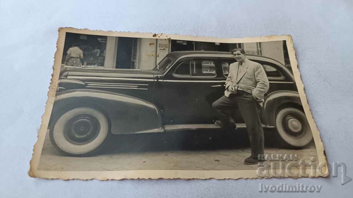 Photo A man in front of a vintage car on the street