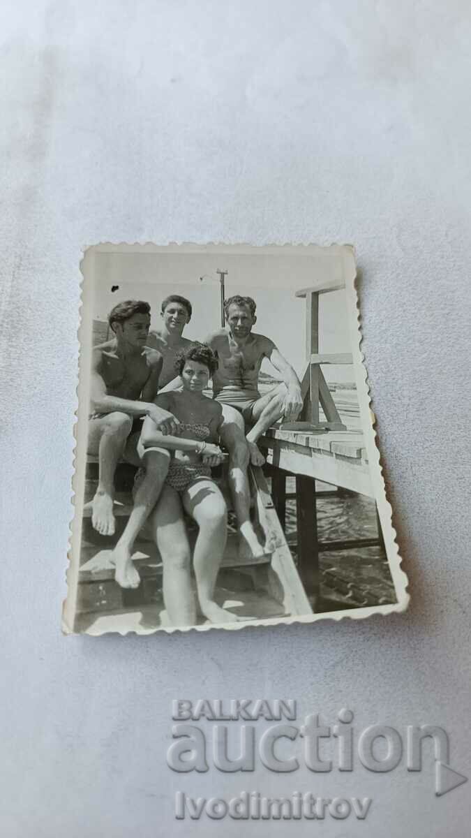 Επισκόπηση φωτογραφίας Τρεις άντρες και ένα κορίτσι στα σκαλιά της προβλήτας 1960