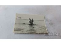 Fotografie Un bărbat și trei femei pe o piatră pe malul mării