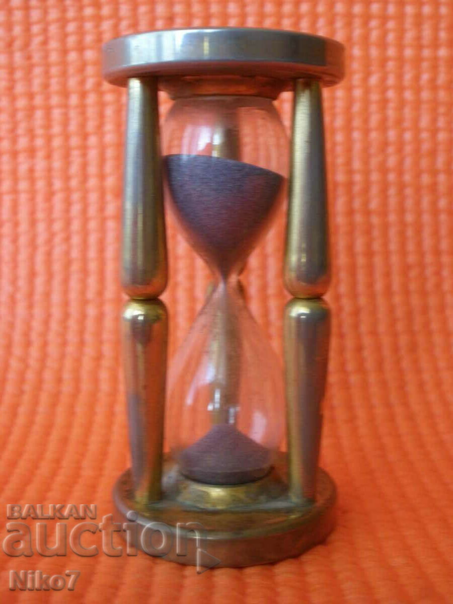A small metal hourglass with two coins.