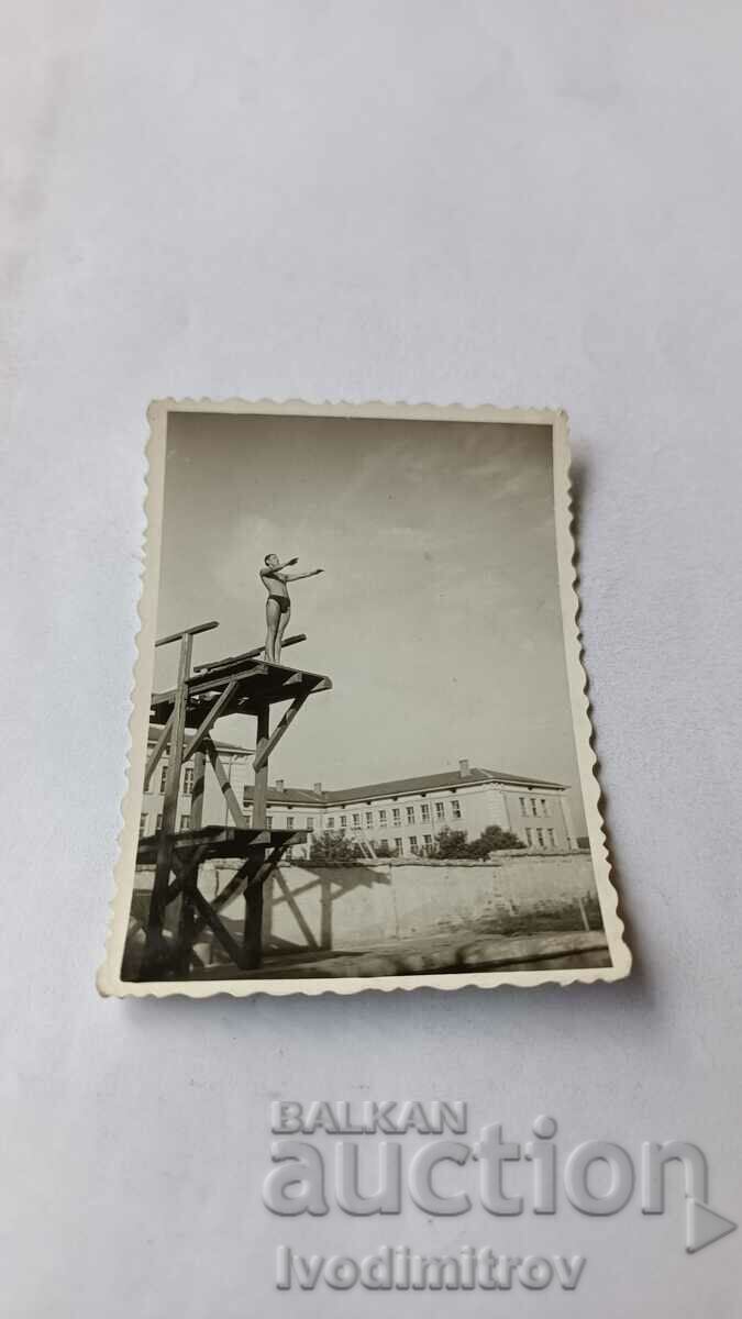 Photo Young man in a swimsuit jumping from a wooden springboard