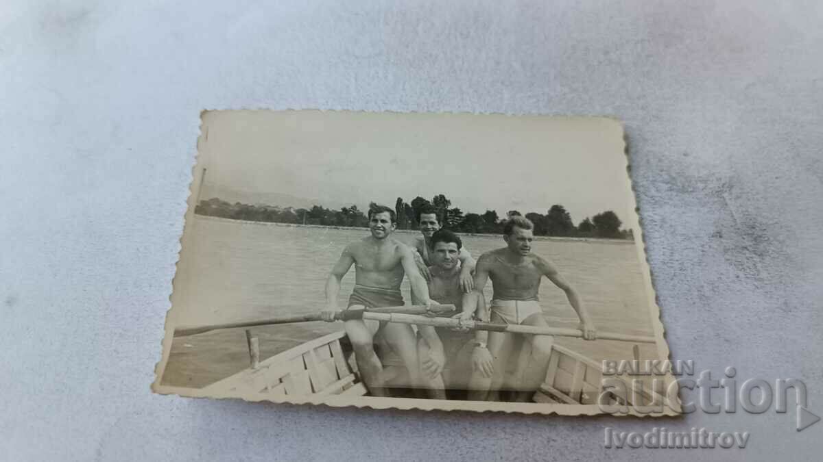 Photo Four young men with a boat in the sea