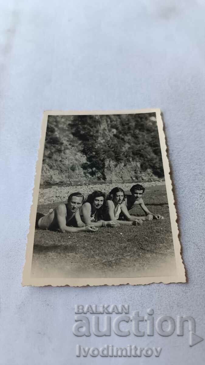 Imagine Două fete tinere și doi bărbați tineri întinși pe iarbă