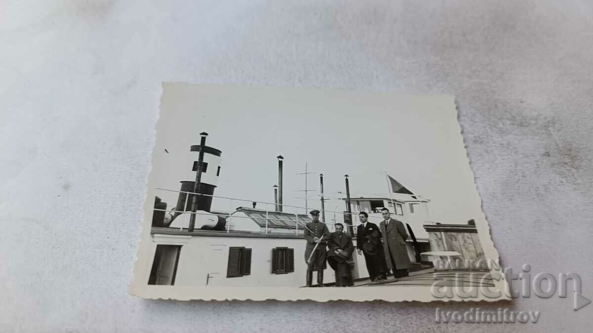 Photo An officer and three men next to a steamer in the harbor