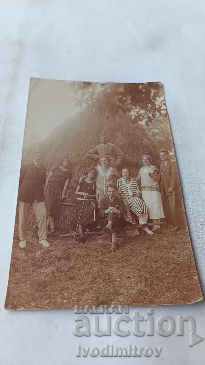 Снимка Мъже и жени пред голяма купа сено
