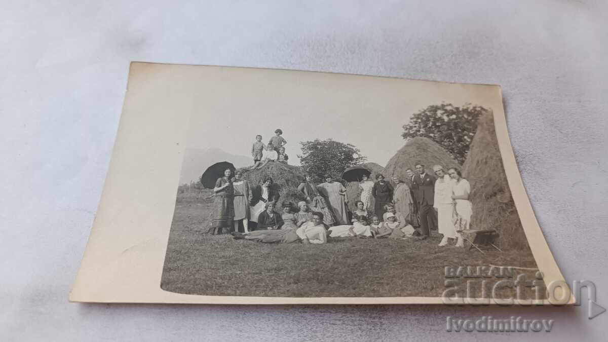 Photo Men women and children in front of haystacks