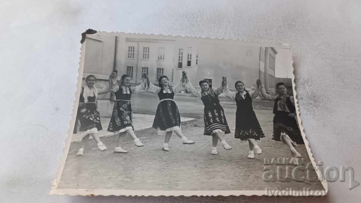 Fotografie Fete tinere în costume populare jucând dans