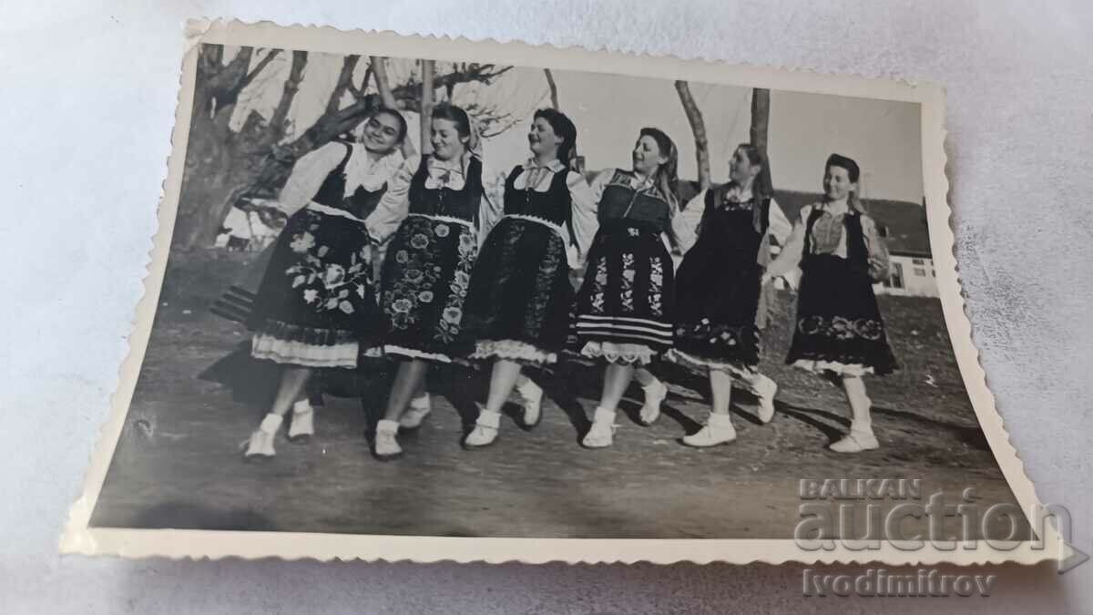 Φωτογραφία Νεαρά κορίτσια με λαϊκές φορεσιές που παίζουν χορό