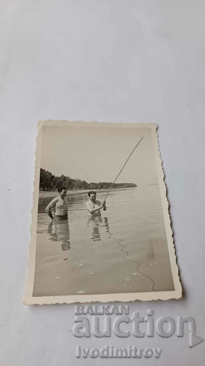 Picture Two men with a fishing rod in the sea